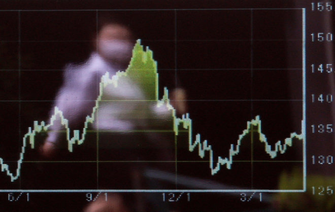 A passerby is reflected on an electric monitor displaying the graph of recent moments of the Japanese yen exchange rate against the U.S. dollar in Tokyo – المضارب العربي