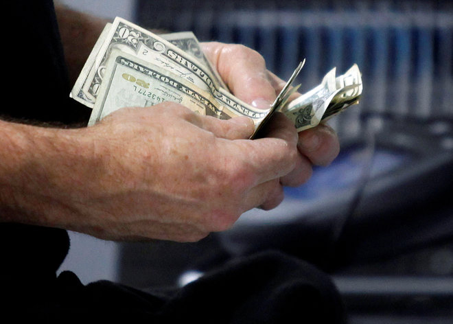 FILE PHOTO: A customer counts his cash at the register while purchasing an item at a Best Buy store in Flushing – المضارب العربي