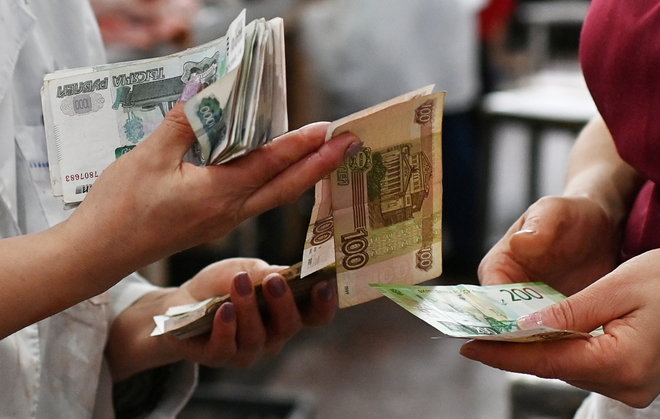 Vendors count Russian rouble banknotes at a market in Omsk – المضارب العربي